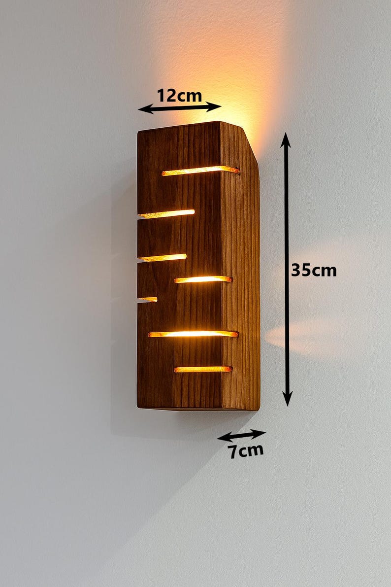 A vertical rectangular wooden wall sconce with warm LED light shining through carved horizontal openings. The wood has a natural grain and rustic brown finish. The style is minimalist, cozy, and modern, suitable for hallway, living room, or bedroom wall lighting.