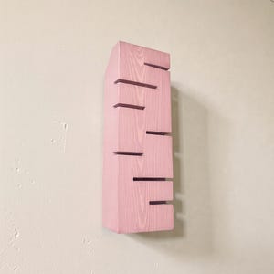 A vertical rectangular wooden wall sconce with warm LED light shining through carved horizontal openings. The wood has a natural grain and rustic brown finish. The style is minimalist, cozy, and modern, suitable for hallway, living room, or bedroom wall lighting.