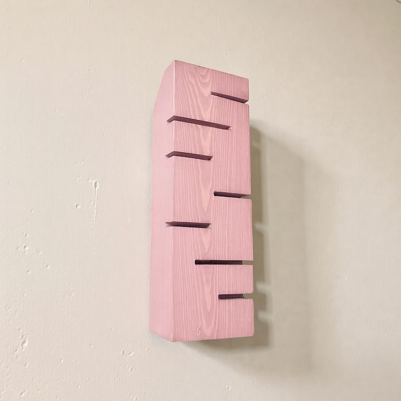 A vertical rectangular wooden wall sconce with warm LED light shining through carved horizontal openings. The wood has a natural grain and rustic brown finish. The style is minimalist, cozy, and modern, suitable for hallway, living room, or bedroom wall lighting.