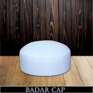 May include: White cotton skullcap with a ribbed texture and a rounded top. The cap is called a "Badar Cap".