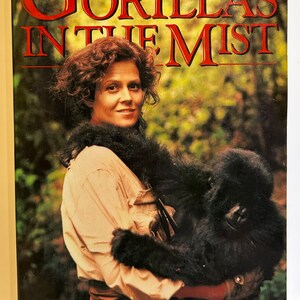 May include: A book cover featuring a woman holding a baby gorilla. The title of the book is "Gorillas in the Mist" and the author is Dian Fossey.