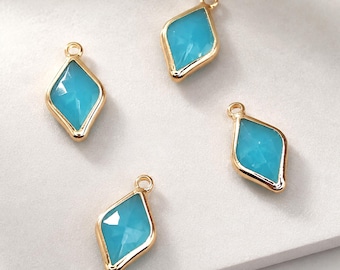 May include: Four diamond-shaped jewelry charms featuring bright turquoise blue stones set in polished gold-tone metal frames. Each charm includes a small circular loop at the top for attachment, showcasing a faceted surface that reflects light.
