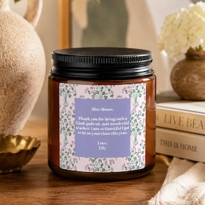 May include: A candle in a glass jar with a black lid. The label reads "Miss Moore. Thank you for being such a kind, patient, and wonderful teacher. I am so thankful I got to be in your class this year. Love, Lily."