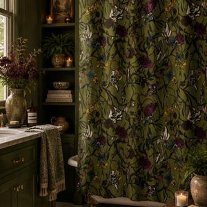 May include: A bathroom with a dark green color scheme, featuring a floral patterned shower curtain. The room includes a vanity, shelves with decor, and a patterned rug. The shower curtain has a botanical design with dark green, purple, and white flowers.