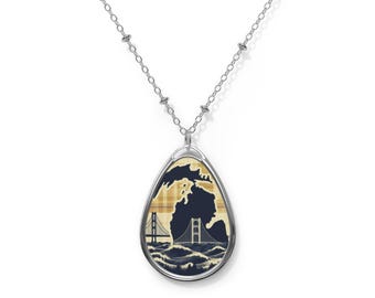 May include: A silver chain necklace with a teardrop-shaped pendant featuring a blue and yellow plaid design with a silhouette of the state of Michigan and a bridge.