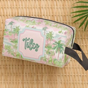 May include: A rectangular cosmetic bag with a tropical print featuring palm trees and a pink and green color scheme. The bag has a black handle and the word "Tiles" in green script on a pink label.