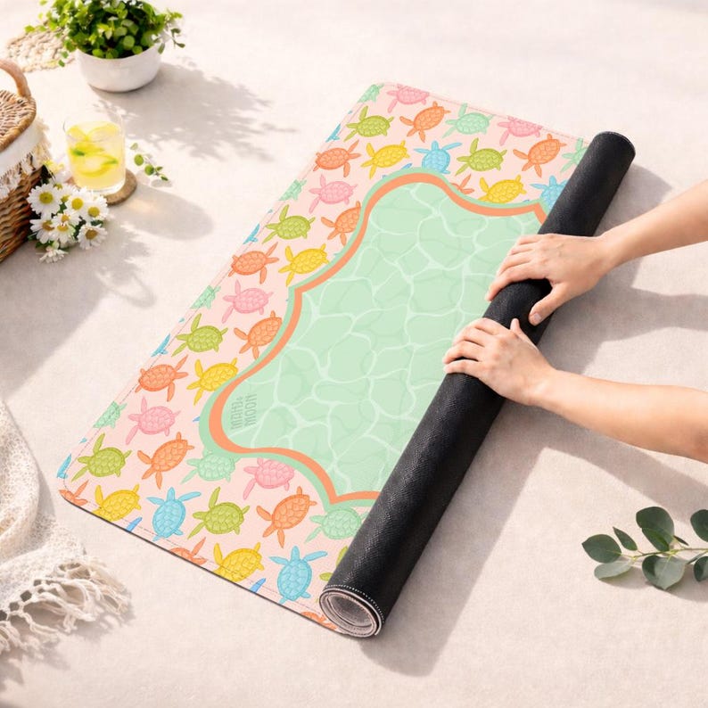 May include: A rectangular yoga mat featuring a repeating pattern of small, colorful sea turtles in shades of pink, orange, yellow, green, and blue on a light background. The center has a large, light green area with a water-like texture.