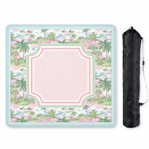 May include: A square mat featuring a tropical palm tree pattern in shades of green and pink, with a central light pink panel displaying a Greek key border and a light blue trim. The text Mahj & Moon is visible. A black carrying bag is included.