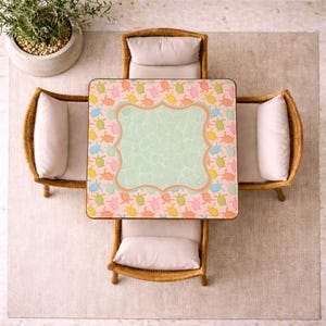 May include: A square table featuring a light pink surface covered in a repeating pattern of small turtles in shades of orange, yellow, green, and blue, with a central light green panel outlined by a decorative orange border.