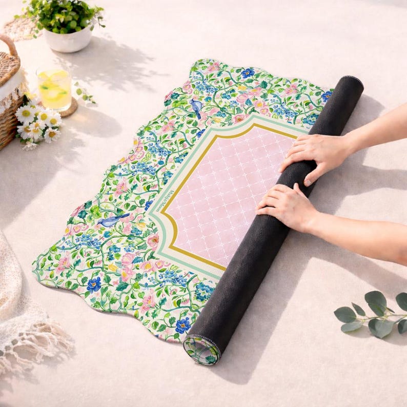 May include: A rectangular desk mat with a scalloped edge featuring a floral pattern of pink and blue flowers, green vines, and small blue birds. The center has a light pink rectangular panel with a white grid pattern and a gold border.