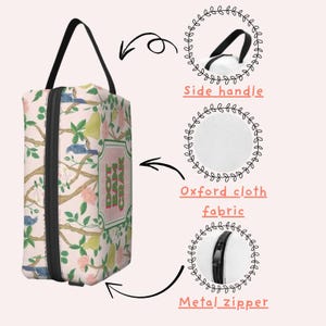 May include: A rectangular cosmetic bag with a black handle and zip. The bag features a floral pattern with birds, pears, and the text "DOT BAM CRAK" on a pink background. The bag is made of Oxford cloth fabric.