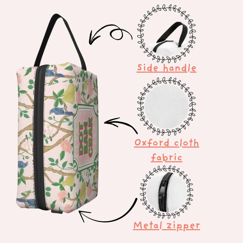 May include: A rectangular cosmetic bag with a black handle and zip. The bag features a floral pattern with birds, pears, and the text "DOT BAM CRAK" on a pink background. The bag is made of Oxford cloth fabric.