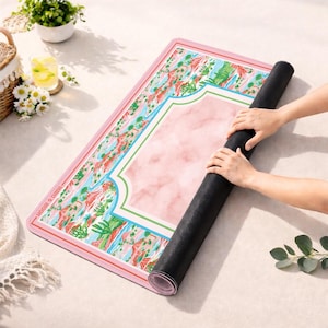 May include: A rectangular yoga mat with a pink marble centre and a border featuring a colourful desert landscape with cacti and rock formations. The mat has a black underside and the text "MAID & MOON" printed along the left side edge.