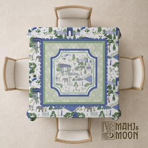 May include: A square tablecloth with a detailed garden scene in shades of blue, green, and white. The design includes elephants, trees, and architectural elements. The tablecloth is set on a wooden table with four chairs.