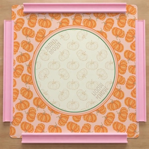 May include: A decorative tray with a pumpkin pattern and pink trim. The tray features a central circular design with the text "MAHU & MOON". The background is a light peach color.
