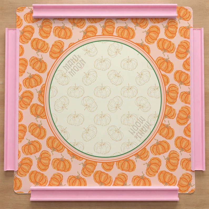 May include: A decorative tray with a pumpkin pattern and pink trim. The tray features a central circular design with the text "MAHU & MOON". The background is a light peach color.