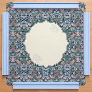 Op de afbeelding: Een vierkant spelbord met een bloemenpatroon in blauw, groen en rood. Het midden heeft een crèmekleurige, sierlijke vorm met de tekst "MAHJ & MOON". Lichtblauwe rails omlijsten het bord. Voor spelletjes.