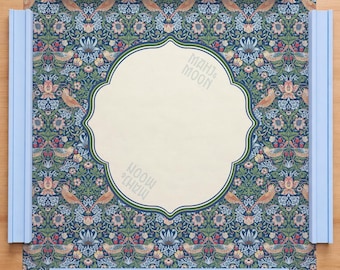 May include: A square game board with a floral pattern in blue, green, and red. The centre has a cream-coloured, ornate shape with the text "MAHJ & MOON". Light blue rails frame the board. The board is likely for a game like Mahjong.