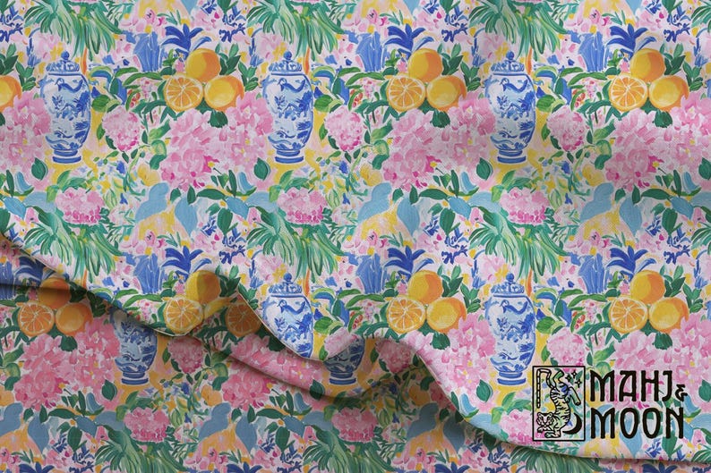 May include: Fabric featuring a repeating pattern of blue and white ginger jars, yellow citrus fruits, and pink floral clusters on a light yellow background. The bottom right corner displays a logo with the text MAHJ & MOON and a tiger illustration.