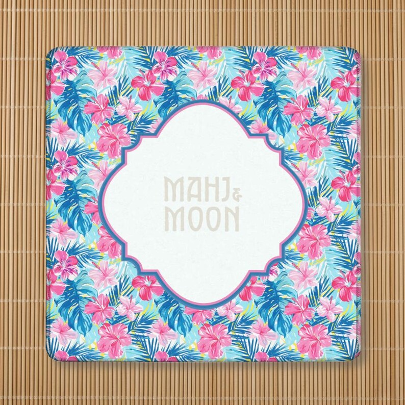 May include: Square coaster with a tropical floral pattern featuring pink hibiscus flowers, blue and green leaves, and the text "MAHJ & MOON" in a white, ornate frame.