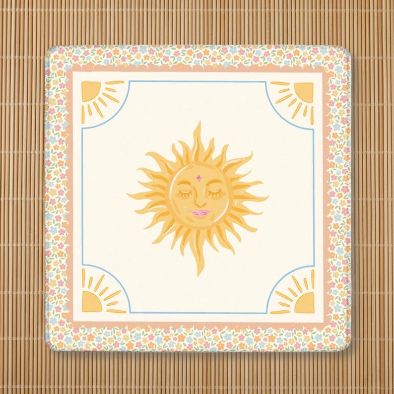 Puede incluir: Posavasos cuadrado con un sol sonriente en el centro. El sol es amarillo con una cara rosa y ojos cerrados. El posavasos tiene un borde floral, un borde interior azul claro y dise&ntilde;os de sol en las esquinas.