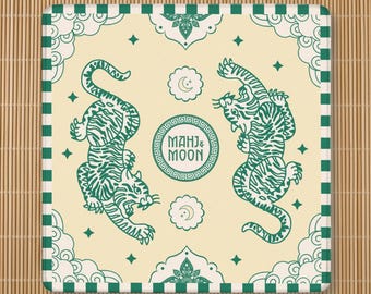 May include: A square coaster with a cream background and a green border featuring a striped pattern. The design includes two green tigers, cloud motifs in the corners, star shapes, and a central circular emblem with the text MAHJ & MOON.