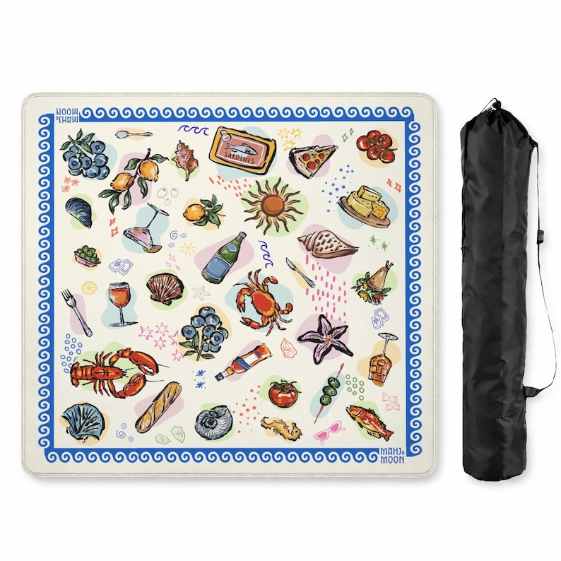May include: A square picnic blanket with a cream background and a blue wave border, featuring colorful illustrations of food, drinks, and sea life, including a lobster, crab, sardines, fruit, and wine glasses. A black carrying bag is included.