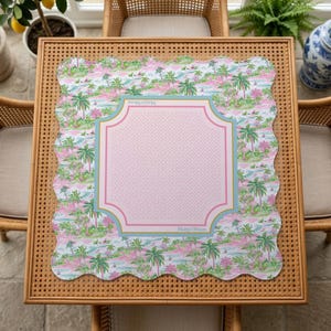 May include: A square scalloped-edge mat featuring a tropical palm tree pattern in shades of pink and green. The centre displays a light pink square with a Greek key border, outlined in blue and pink, with the text Mahjong Moon printed on it.