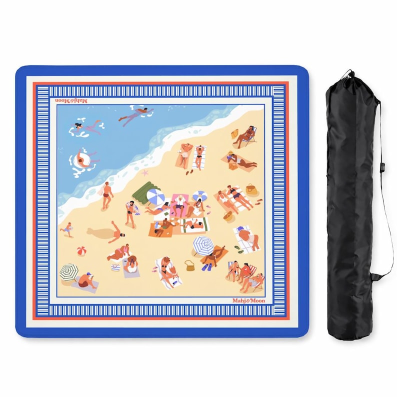 May include: A square beach mat with a blue border and a detailed illustration of a beach scene with people sunbathing, swimming, and relaxing. The mat includes the text "Mahjo & Moon" and comes with a black carrying bag.