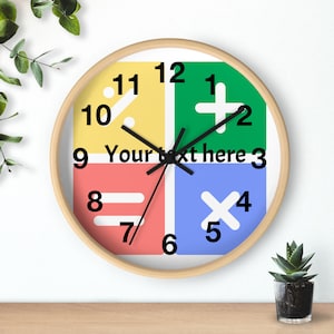 May include: A round wall clock with a light wood frame. The clock face is divided into four quadrants of yellow, green, red, and blue. Each quadrant features a math symbol and a number. The text "Your text here" is in the center.
