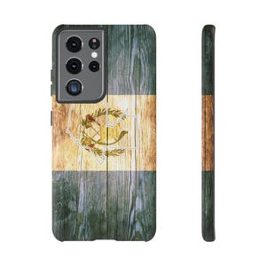 Puede incluir: Una funda de teléfono con el diseño de la bandera guatemalteca. La funda tiene una textura de vetas de madera con los colores de la bandera: azul, blanco y dorado. La funda se muestra desde el frente y el lateral, mostrando el diseño y la cámara del teléfono.