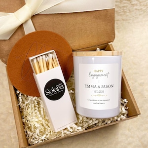 Może przedstawiać: Biały ceramiczny kubek z czarnym uchwytem i napisem "But First, Coffee" czarną, odręczną czcionką. Kubek stoi na białej powierzchni.