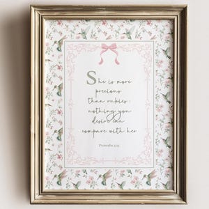 May include: A framed print with a gold-colored frame. The print features a floral and hummingbird pattern with the text "She is more precious than rubies; nothing you desire can compare with her." The words "FOX & FAERIE Paperie" and "Vintage Inspired" are also visible.