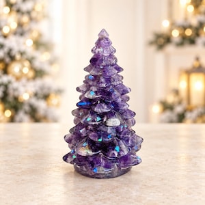 May include: A conical sculpture shaped like a pine tree, crafted from polished purple amethyst stone. The surface features layered, scalloped branches with embedded iridescent blue flecks that catch the light, creating a shimmering effect.