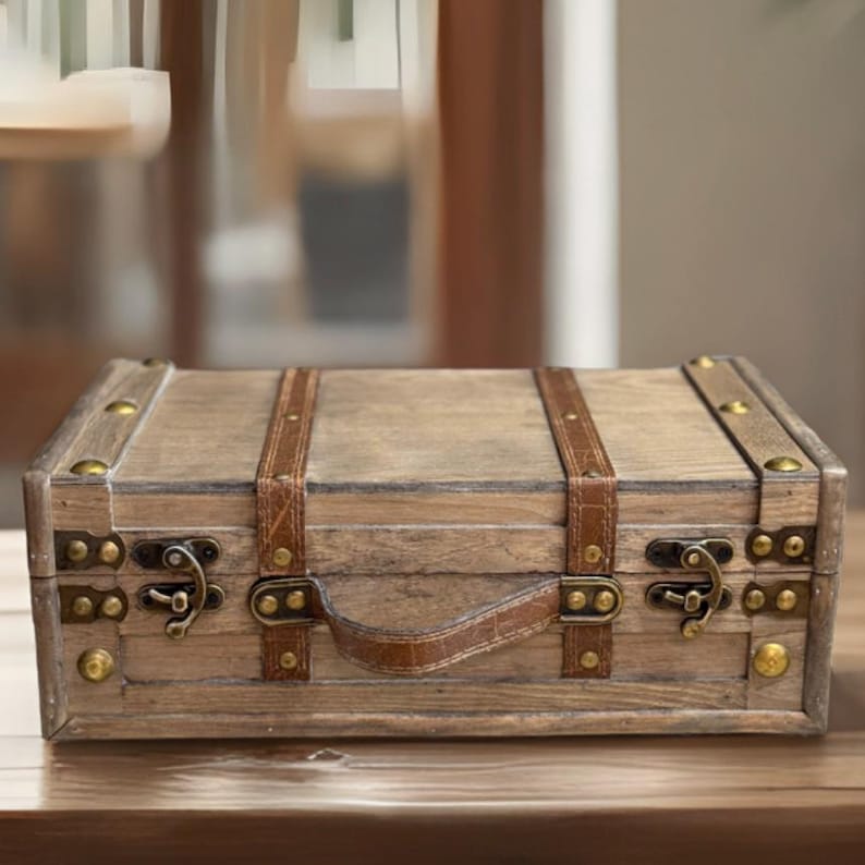 May include: A wooden box with a leather handle and brass accents. The box has a distressed finish and is perfect for storing small items.