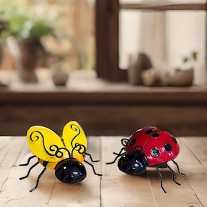 May include: Two metal garden insect figurines. A yellow and black bee with curled antennae and a red and black ladybug with black spots.