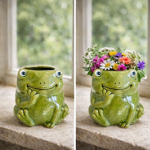 May include: A green ceramic frog-shaped planter with a smiling face and blue eyes. The planter is filled with colorful flowers, including daisies, and is sitting on a stone windowsill. The frog has its hands on its chin.