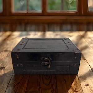 May include: A black wooden box with a hinged lid and a metal latch. The box has a distressed finish and is decorated with metal accents.
