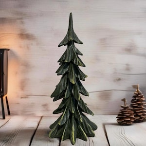 Könnte beinhalten: Ein dunkelgrüner Weihnachtsbaum-Anhänger aus Holz mit rustikalem Finish. Der Baum besteht aus geschichteten Holz und hat eine spitze Spitze.