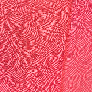 Può includere: Primo piano di un tessuto rosso con un motivo a pois bianchi. I punti sono disposti in linee curve, creando un aspetto strutturato. Il tessuto è piegato, mostrando profondità e dimensione.