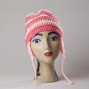 May include: Pink and white striped crocheted hat with long ties. The hat is on a mannequin head.