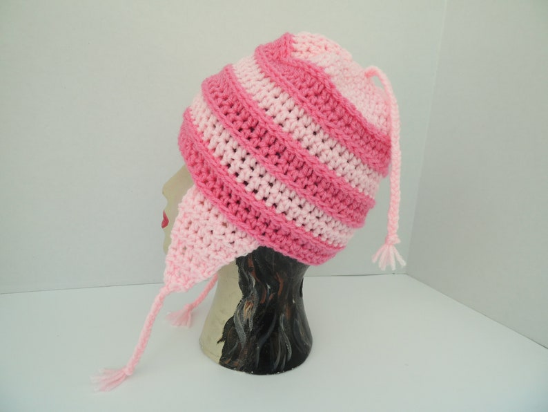 May include: Pink and light pink striped crocheted hat with ear flaps and a long tassel.
