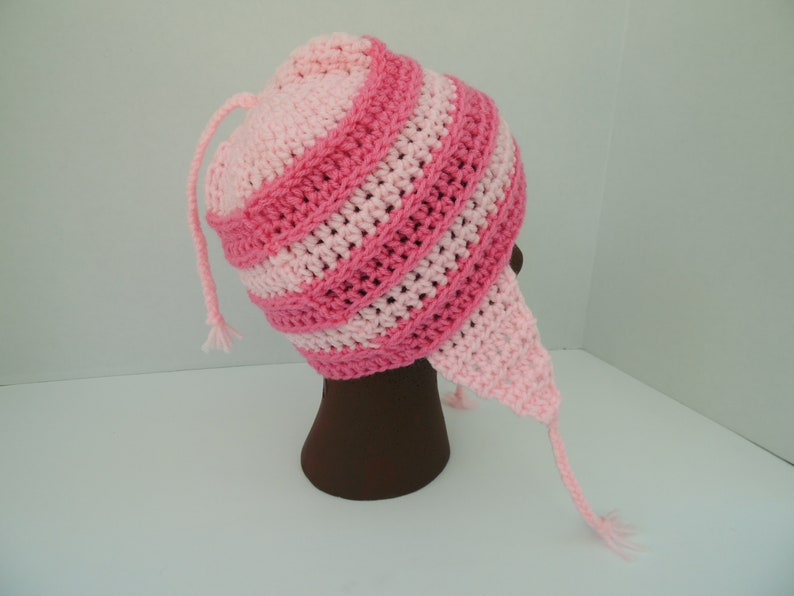 May include: Pink and light pink striped crocheted hat with a long tail. The hat is on a brown mannequin head.