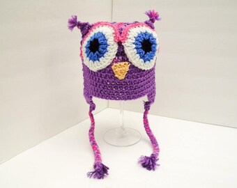May include: Purple crocheted owl hat with pink, white, and blue accents. The hat has long ties that can be tied under the chin.