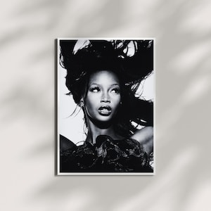 Può includere: Stampa di ritratto in bianco e nero di una donna con lunghi capelli fluenti. L'immagine è un primo piano, che si concentra sul viso e sulla parte superiore del corpo della donna. Indossa un capo scuro e strutturato. La stampa è incorniciata in un bordo bianco.