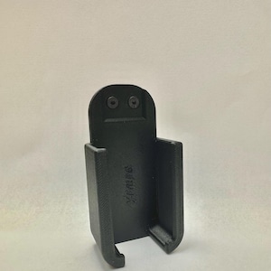 May include: A black 3D-printed holder with a rectangular shape and rounded edges. The holder has a slot for an item to be placed inside. Two screws are visible at the top. The text "Yimix" is printed on the side.