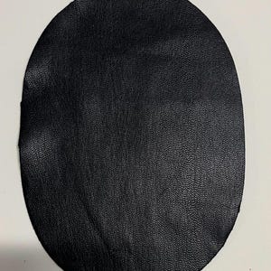 May include: A black leather circle, approximately 4 inches in diameter, with a textured surface.