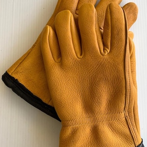 May include: A pair of brown leather work gloves with black trim. The gloves are made of a soft, supple leather and have a comfortable fit.