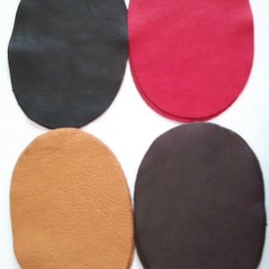 May include: Four leather patches in different colors: black, red, brown, and dark brown. The patches are oval shaped and have a textured surface.