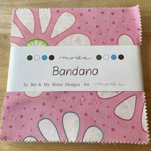 Peut inclure: Carré de tissu rose avec un motif floral blanc et de petits points roses. Le tissu porte une étiquette qui indique "moda Bandana by Me & My Sister Designs for moda".